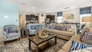 A spacious living room with a large sofa, a coffee table, and a dining area with a kitchen in the background. - Solterra Sunshine - 5* - South facing large pool/spa - game room, gated resort (Davenport)