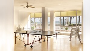 A spacious room with a ping pong table, white chairs, a ceiling fan, large windows with a view of the ocean, and a balcony with white chairs. - LIDER, 4-D (Cullera)