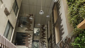 Ein mehrgeschossiges Interieur mit Treppe, Metallgeländern und hängenden Pendelleuchten.