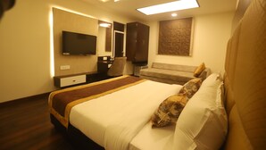 Ein modernes Hotelzimmer mit einem großen Bett, einem Flachbildfernseher, einem Schreibtisch und einer Couch.