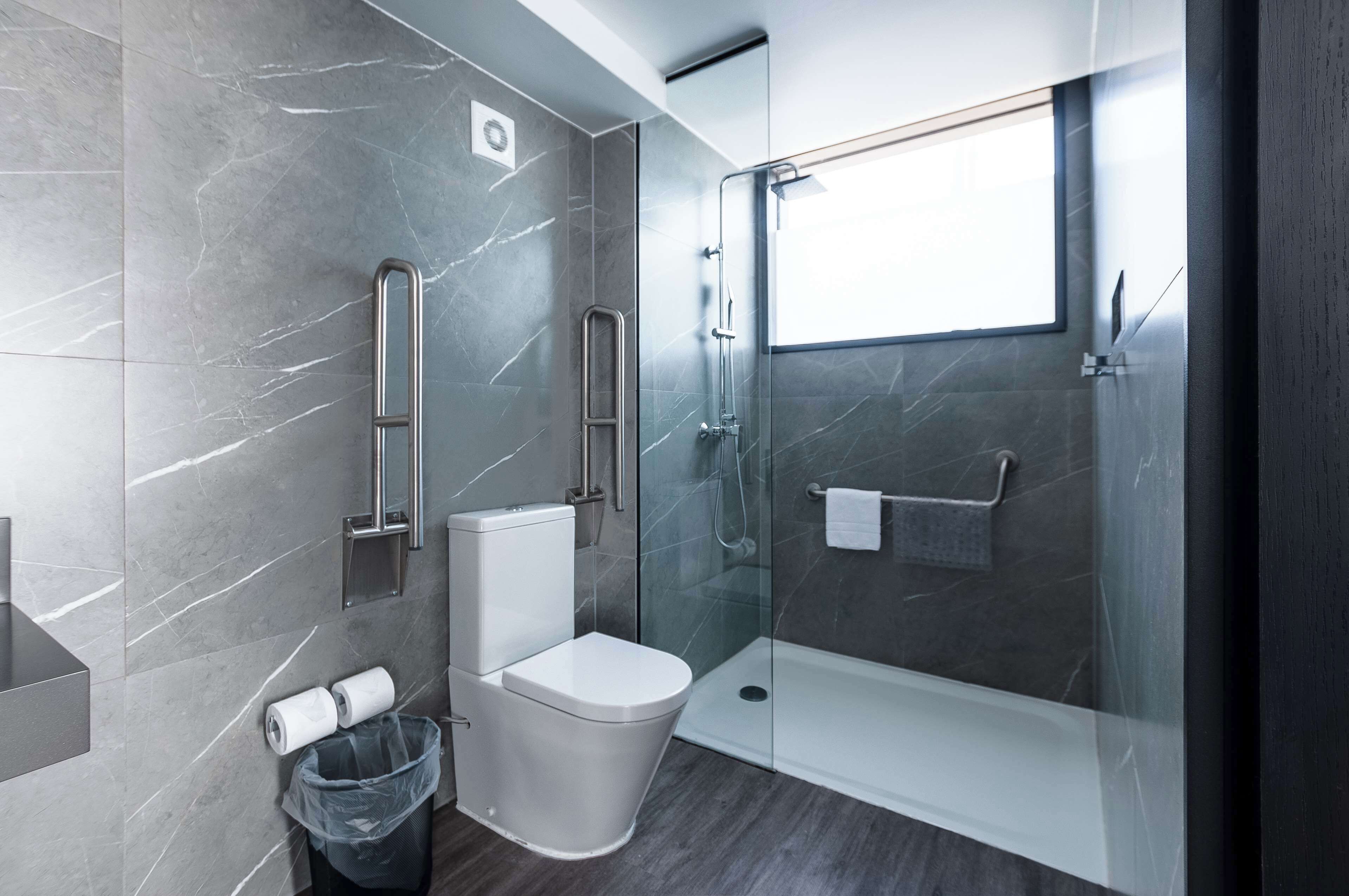 Un baño moderno con ducha de vidrio, inodoro y cubo de basura.