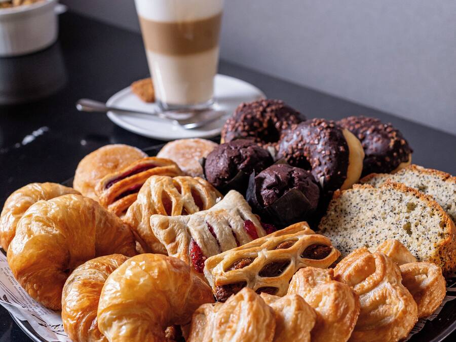 Une assiette remplie de diverses pâtisseries et une tasse de café sur une table.