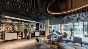A modern lobby with a reception desk, seating area, and large windows offering views of the outside.