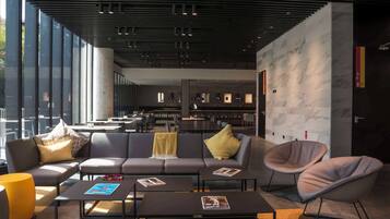 A modern lounge area with a sofa, armchairs, and coffee tables.