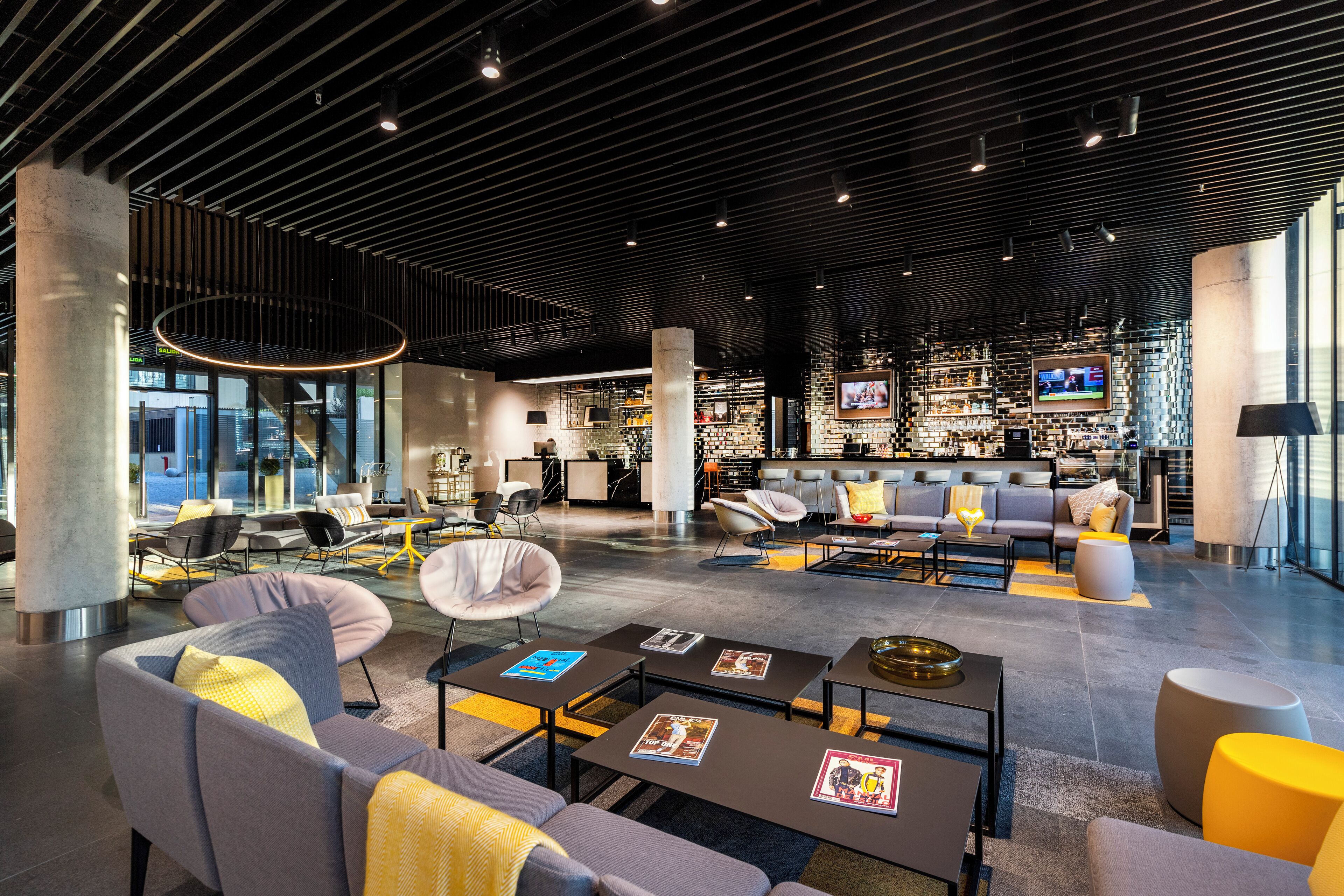 A modern lounge area with seating, tables, and a bar.