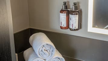 A bathroom with two CAVA bottles, a towel rack with rolled towels, and a mirror.