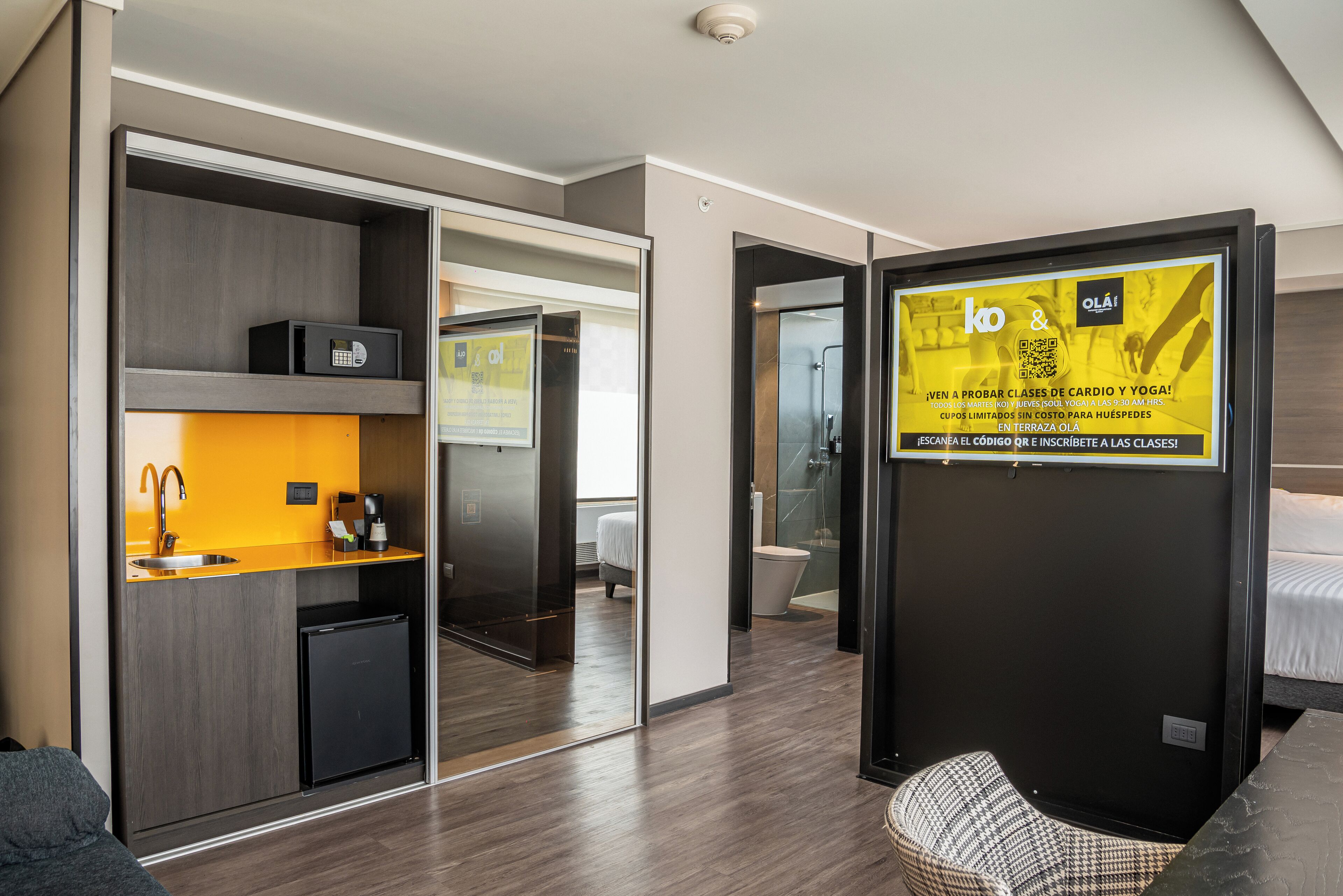 Una habitación de hotel moderna con kitchenette, zona de ducha y cama.