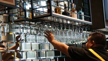 Un cantinero organiza vasos en una estantería en un bar.