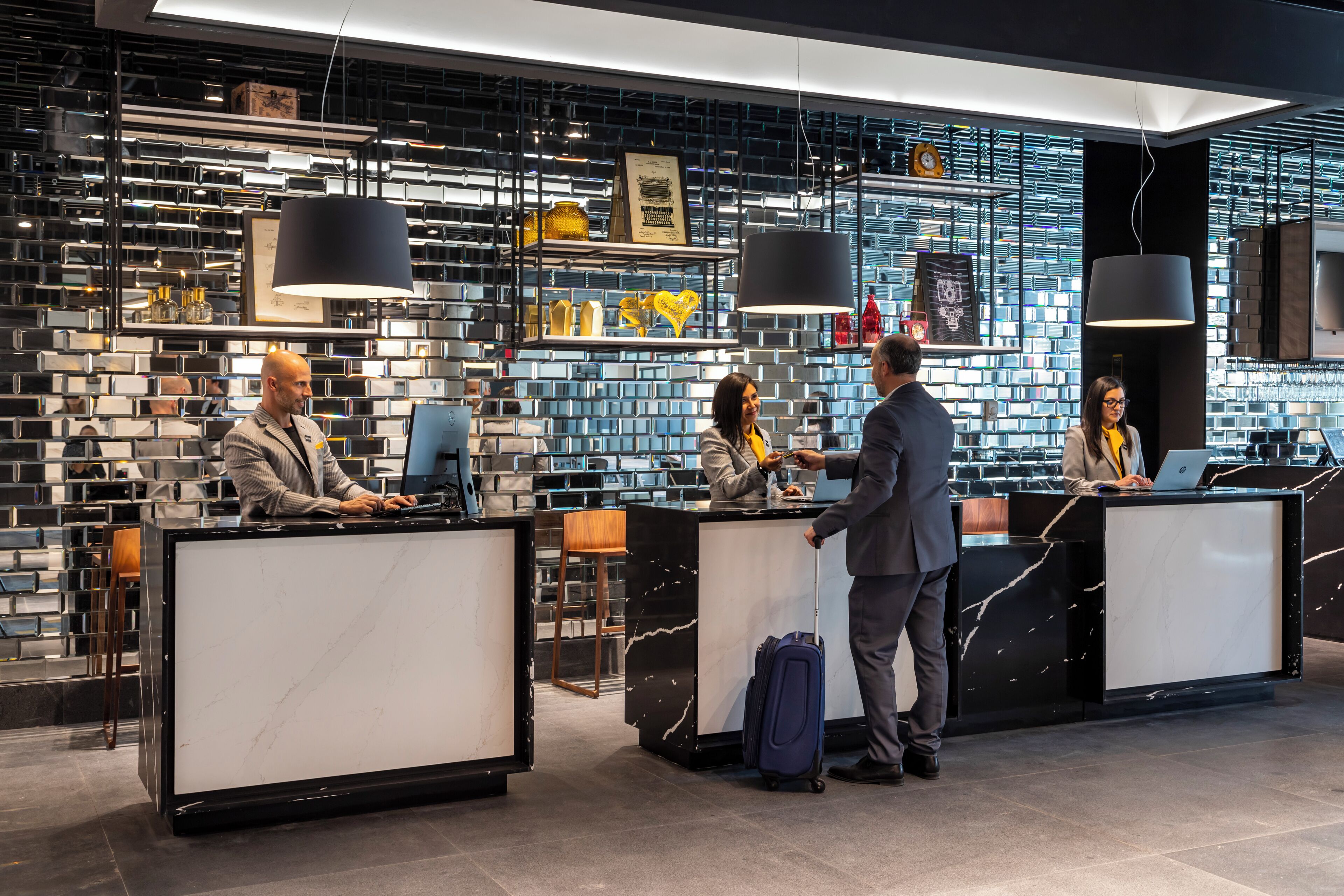 A modern reception area with marble counters, a brick-patterned wall, and pendant lighting.