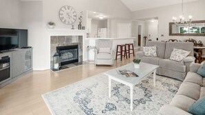 A modern living room with a fireplace, a television, and a sofa. - Lake Norman Luxury Waterfront 3rd floor Condo with Elevator, Pool, Tennis (Cornelius)