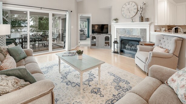 A spacious living room with a large TV, a fireplace, and a dining area with outdoor seating. - Lake Norman Luxury Waterfront 3rd floor Condo with Elevator, Pool, Tennis (Cornelius)
