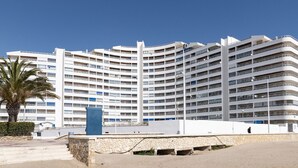 Un hotel a più piani con una facciata curva, balconi e una palma sullo sfondo.