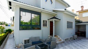 Een modern huis met een terras, wicker meubels en een betegelde vloer.