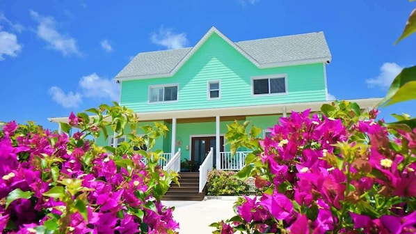 A two-story house with a green exterior and a white porch.
