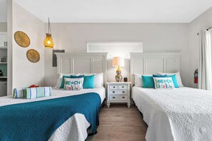 Ein Hotelzimmer mit zwei Betten, einem Nachttisch mit Lampe und einem Fenster mit Jalousien.