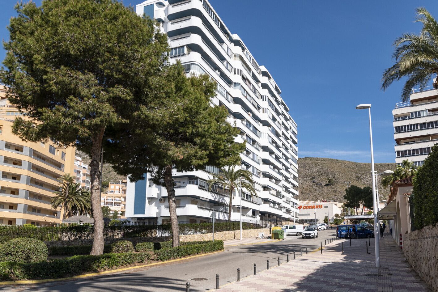 Un hôtel à plusieurs étages doté de balcons, d’un trottoir pavé et surplombant un ciel dégagé.