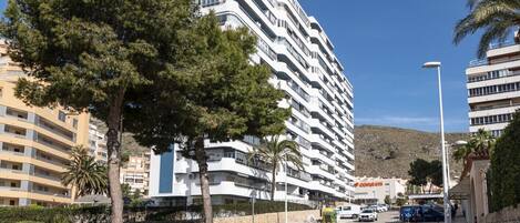 Un hôtel à plusieurs étages doté de balcons, d’un trottoir pavé et surplombant un ciel dégagé.