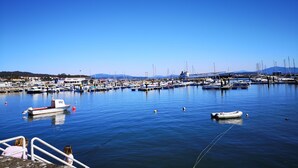 A marina with boats docked, a clear blue sky, and a distant mountain range. - Casa Maria in Palmeira (Ribeira)