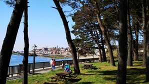 A park with picnic tables and a view of a town across a body of water. - Casa Maria in Palmeira (Ribeira)