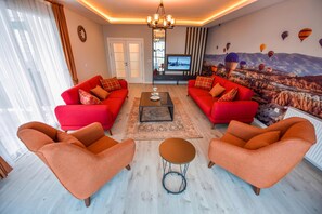 A living room with red sofas, a coffee table, and a mural of hot air balloons.