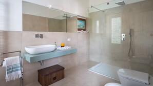 Une salle de bain moderne avec un grand lavabo, une douche à parois de verre et des toilettes.
