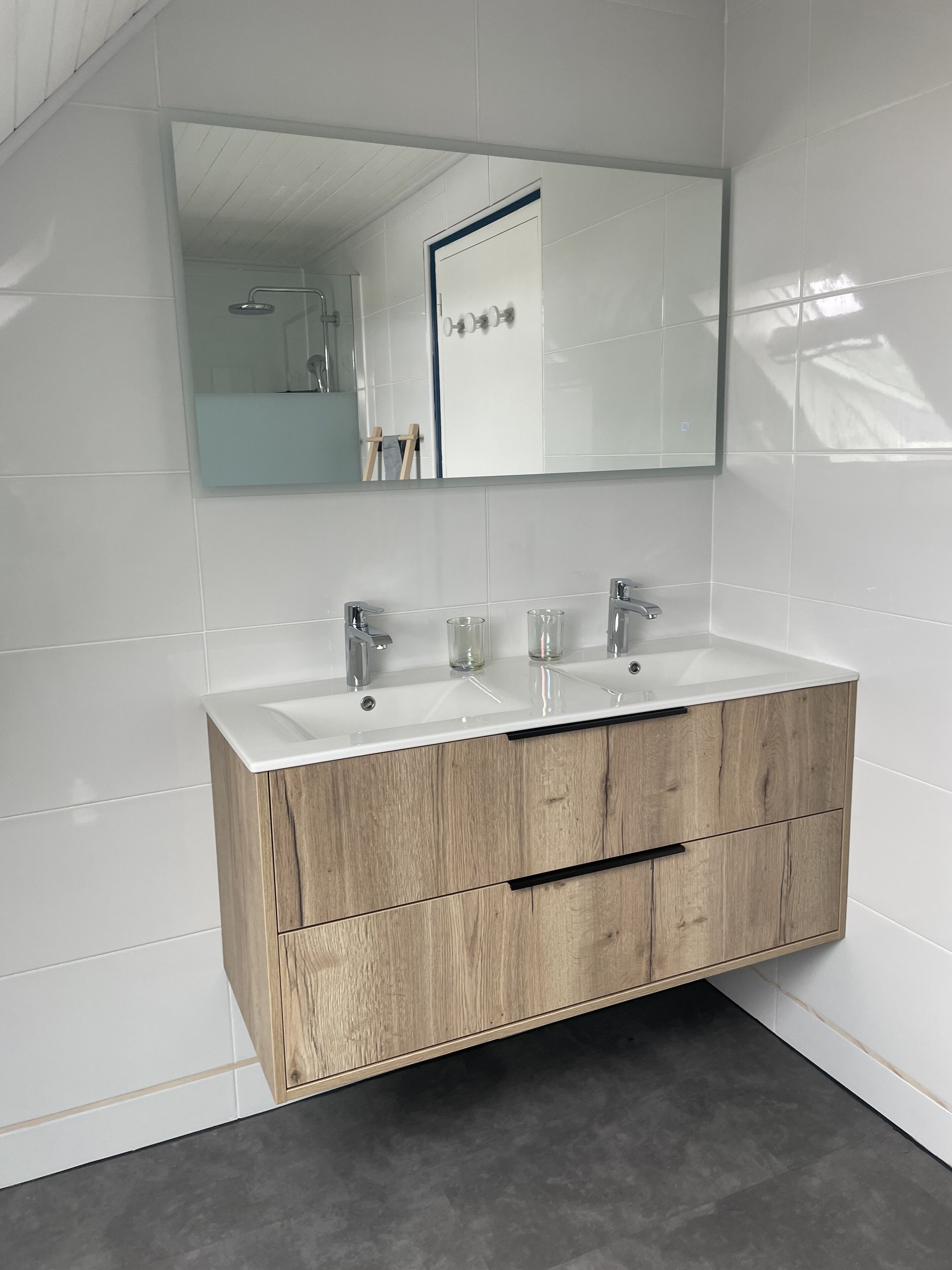 Un baño con tocador de madera, dos lavamanos y un espejo grande.