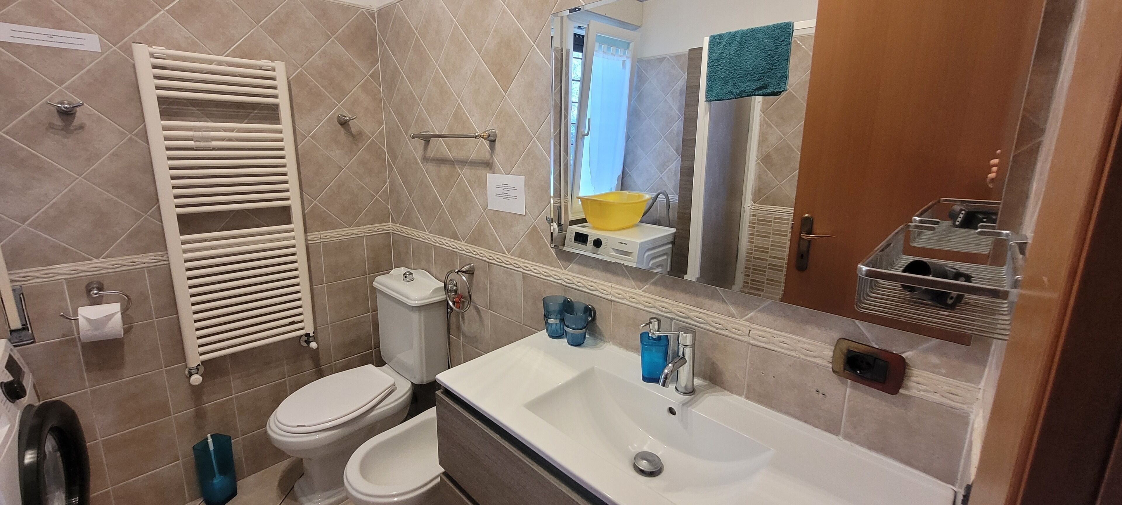 A bathroom with a toilet, bidet, sink, and towel rack.