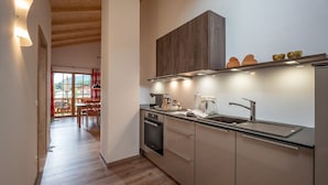 Eine moderne Küche mit Holzbalken, einem Backofen und einer Spüle aus Edelstahl.