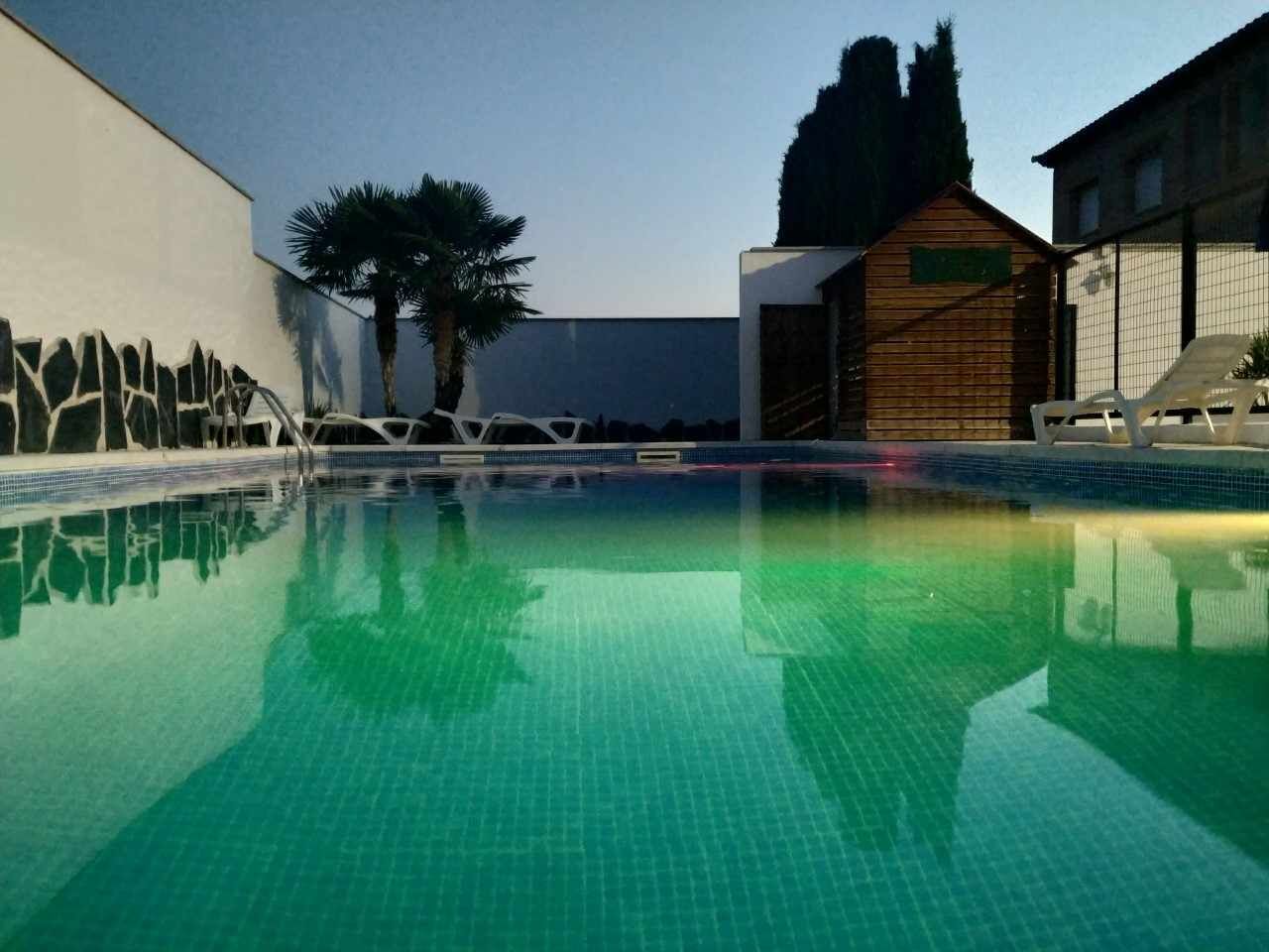 A swimming pool with clear water, surrounded by modern architecture and palm trees.