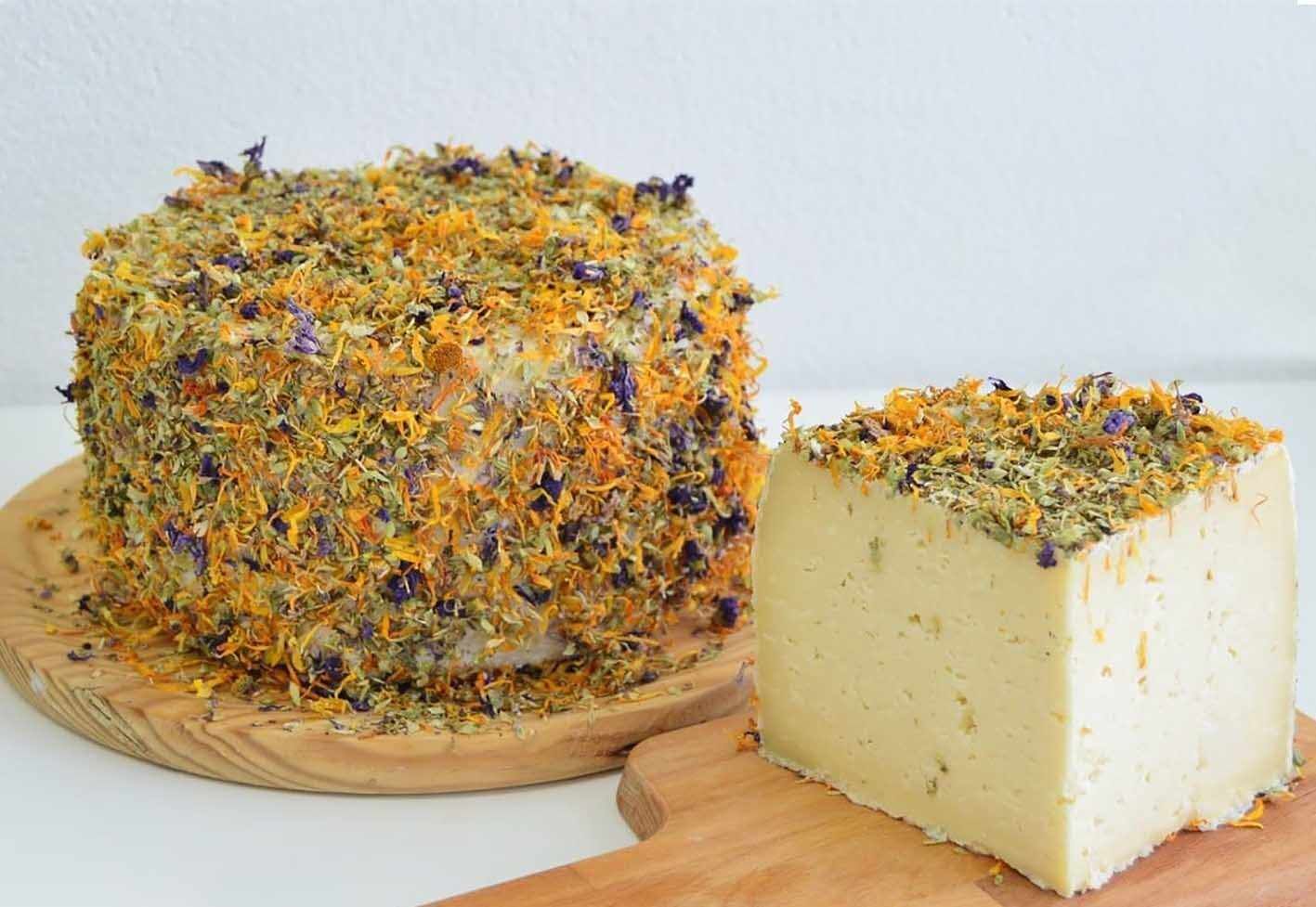 A large, round, cheese wheel with a wooden board underneath.