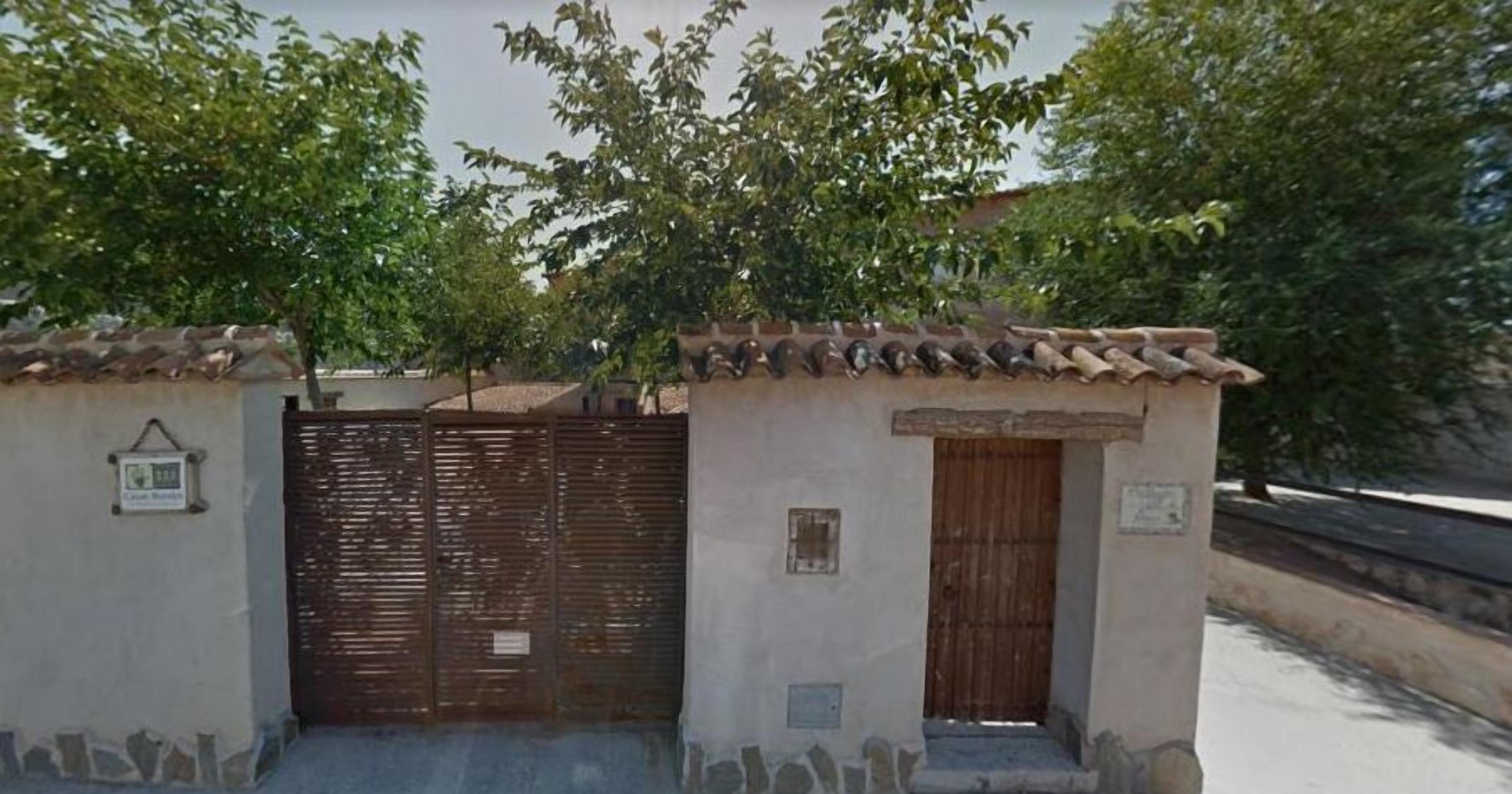 Un edificio pequeño con techo de tejas, puerta de madera y reja de metal.