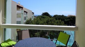 Ein Balkon mit Tisch und Stühlen, mit Blick auf eine Wohngegend mit Bäumen und Gebäuden.