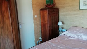 A bedroom with a bed, a wooden wardrobe, a door, and a small table with a lamp. - Ocean View!! One-bedroom apartment with a garage!! "Mobility Lease" rental. (Saint-Malo)