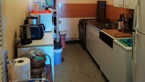 A compact kitchen with a refrigerator, sink, and a countertop with various items. - Ocean View!! One-bedroom apartment with a garage!! "Mobility Lease" rental. (Saint-Malo)