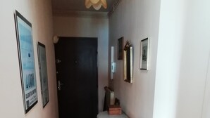 A narrow hallway with wooden flooring, a dining table with chairs, and a ceiling light fixture. - Ocean View!! One-bedroom apartment with a garage!! "Mobility Lease" rental. (Saint-Malo)