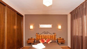 Un dormitorio ordenado con una cama grande, cabecera de madera, mesitas de noche y una mesilla.