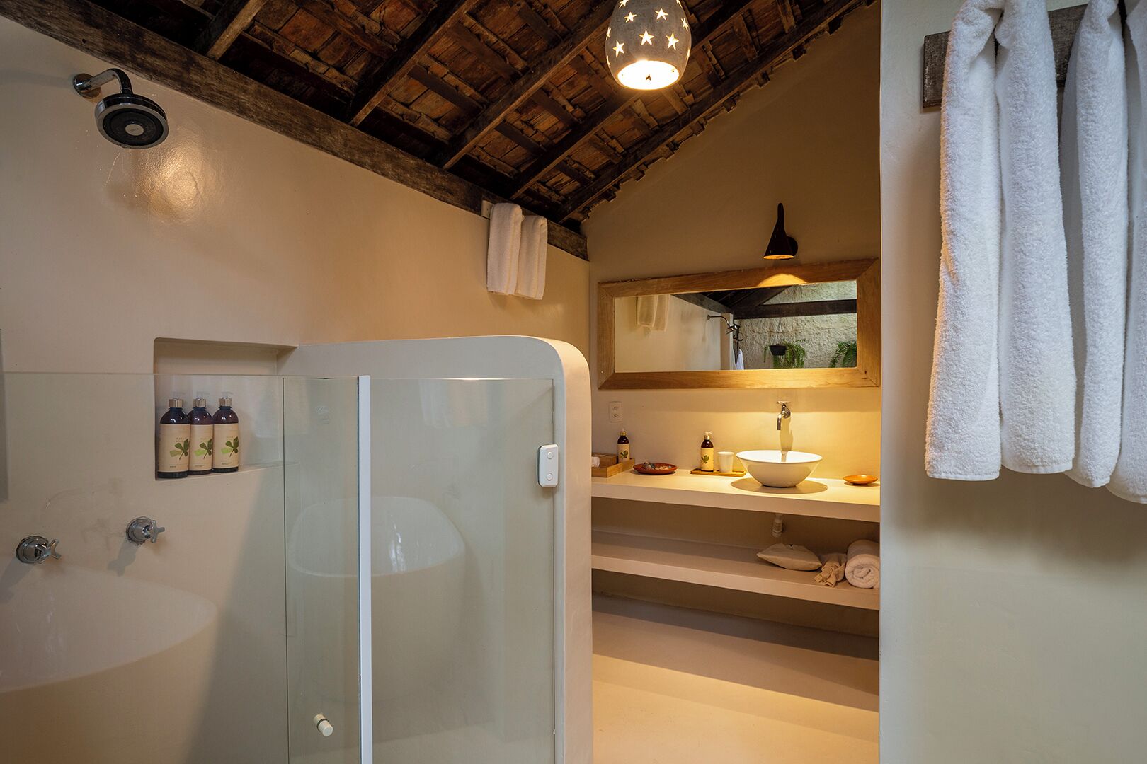 A bathroom with a glass-enclosed shower, a sink with a mirror above it, and a towel rack.