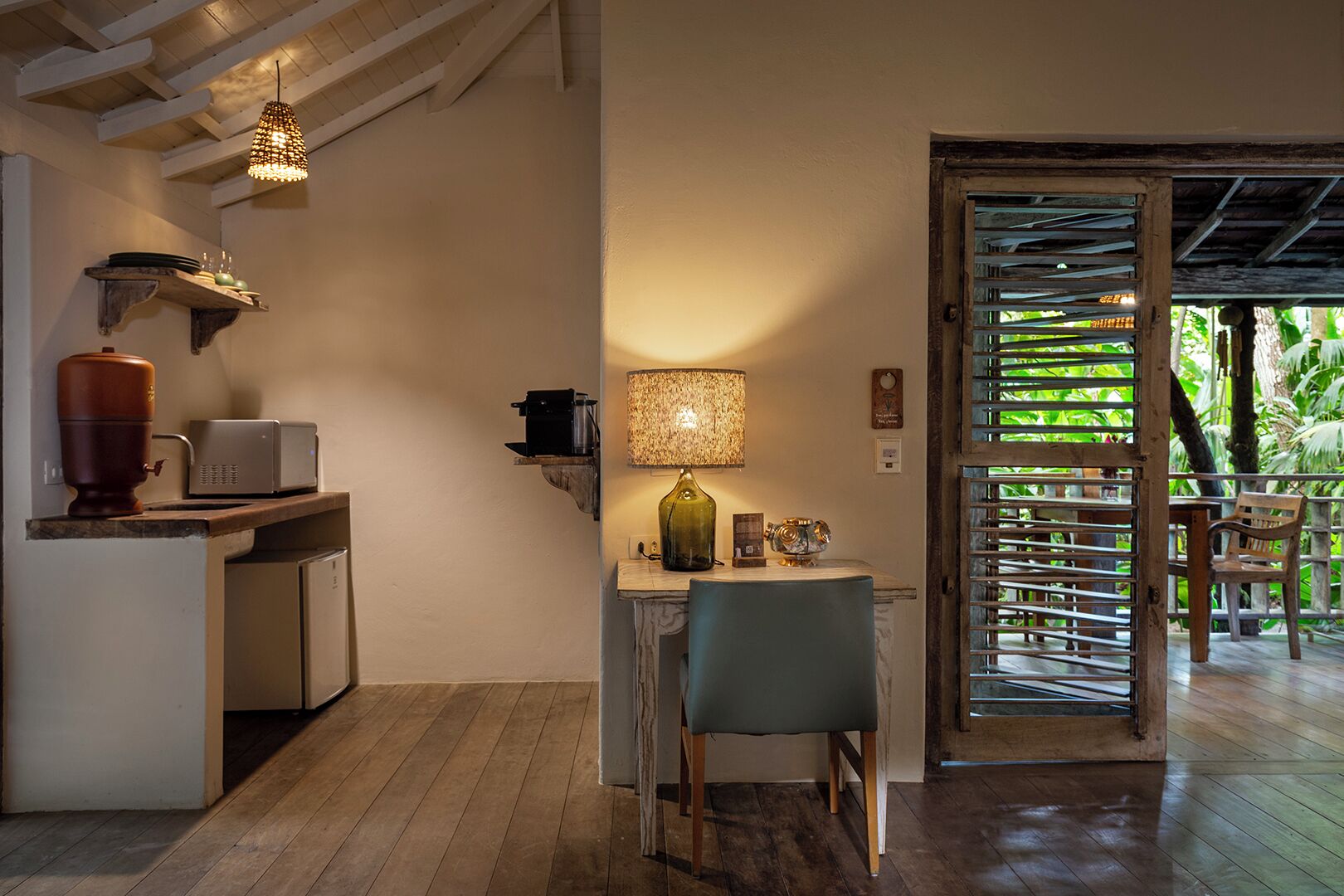 Une cuisine chaleureuse avec une table en bois, une chaise, une lampe et un distributeur d’eau.
