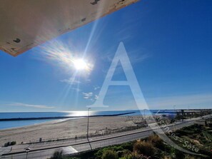 A beach with a clear sky, a road, and a large 'A' watermark. - T2 CLASSÉ AVEC TERRASSE, VUE MER, CLIM (Sète)