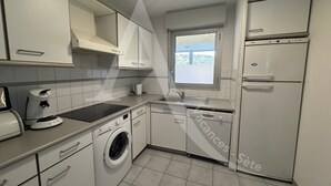 A compact kitchen with a washing machine, a sink, and a window.