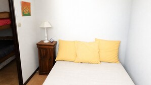 A room with a bed, a nightstand with a lamp, a wall clock, and a painting.