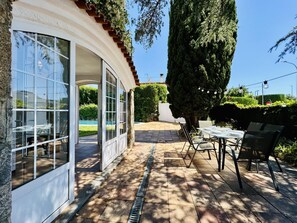 En patio med udendørs møbler, en swimmingpool og et højt træ.