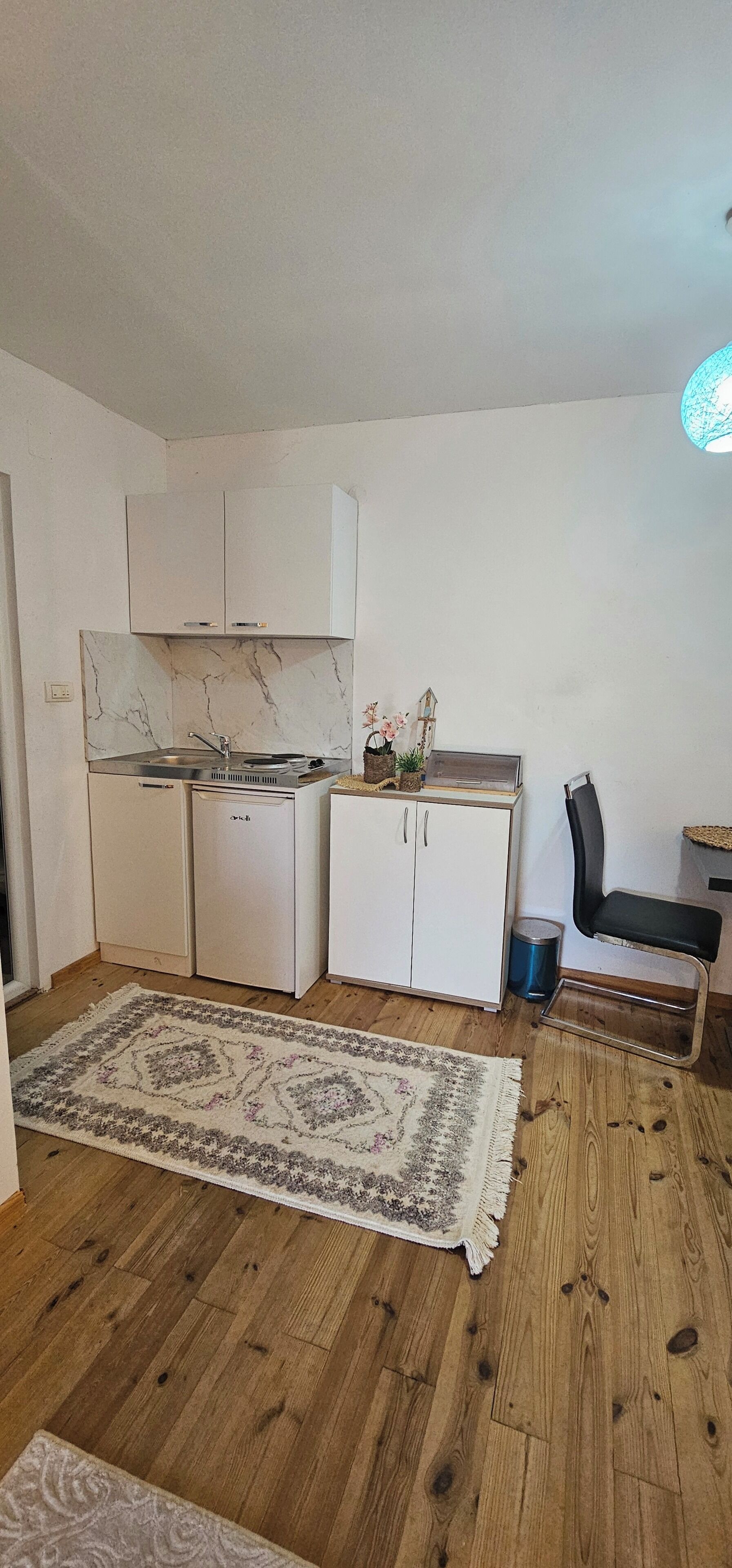 Une cuisine compacte avec des meubles blancs, une cuisinière intégrée et un petit réfrigérateur.