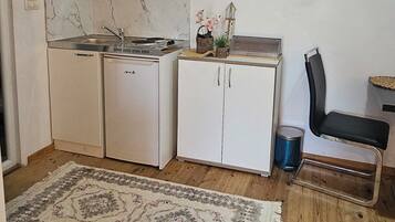 Une cuisine compacte avec des meubles blancs, une cuisinière intégrée et un petit réfrigérateur.