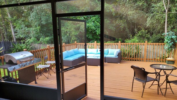 Un patio abierto con una parrilla, zona de estar y vistas al entorno verde.
