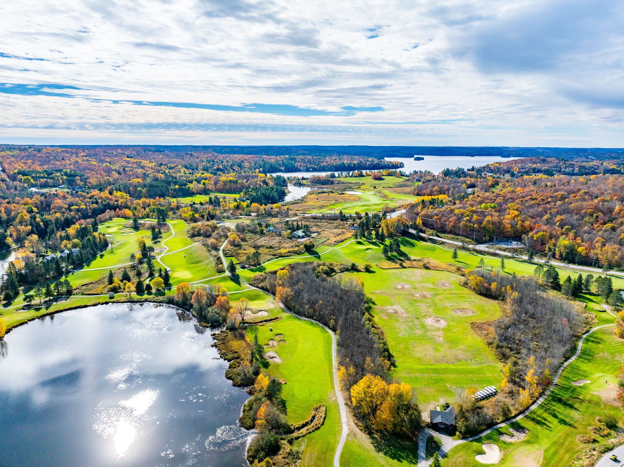 Ilmakuva golfkentästä, jonka vieressä on järvi ja jota ympäröi syksyinen lehtipuuvalle.