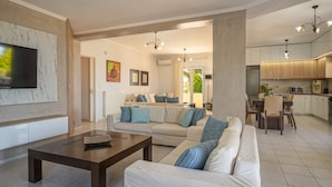 A modern living room with a sofa, coffee table, and a TV mounted on the wall.