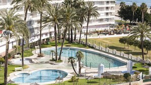Een resort met een groot zwembad, palmbomen en uitzicht op de oceaan.