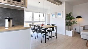 Une cuisine moderne équipée d’un four à micro-ondes encastré, d’une machine à café et d’un coin repas avec une table et des chaises en bois.