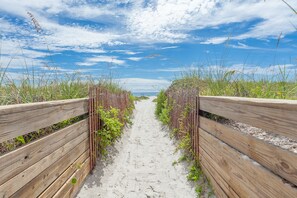 A sandy pathway flanked by wooden fences and vegetation, leading towards a beach. - Highly rated Condo in Ocean Front Community, Wheelchair accessible, Dog friendly (St Augustine Beach)